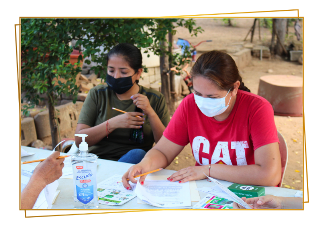 consentimeinto 2 Mujeres leyendo, revisando y firmando documentos como parte de un proceso de consentimiento informado comunitario.